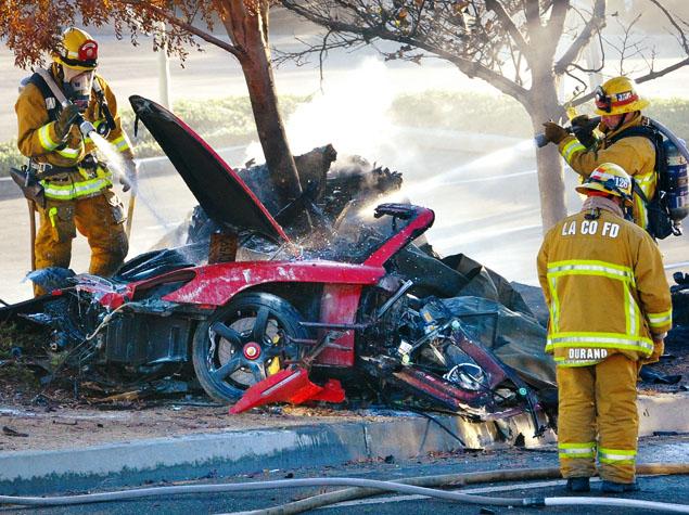 Firefighters spray water on the wreckage of the Porsche that crashed in Valencia, Calif., on Saturday. 